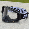 Black and white retro motorcycle sunglasses with night vision lenses resting on a gray surface.