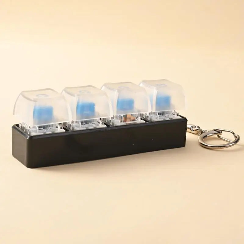A black LED mechanical keychain fidget toy with multiple clear and blue keycaps is shown on a light background.