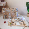A wooden Montessori busy board featuring various manipulative parts and tools for toddlers.