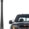 A black universal car radio antenna is shown next to a black pickup truck grille.