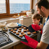 A man is using red silicone oven mitts to handle baked goods in a kitchen setting.