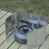 A portable aluminum alloy windshield designed for camping stoves, shown resting on a wooden surface.