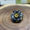 A close-up shot of a black and gold precision metal fidget spinner resting on a wooden surface.