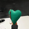 A hand holds a green heart-shaped PU coin purse with a leather wrist strap against a dark background.