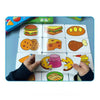 A hand is holding several colorful puzzle cards featuring various food items like hamburgers, fruits, and vegetables on a blu