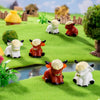 A collection of adorable resin Highland cow figurines in white and reddish-brown colors displayed on green grass.