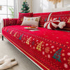 A vibrant red Christmas tree patterned chenille sofa cover displayed on a bed with white and gold accents.