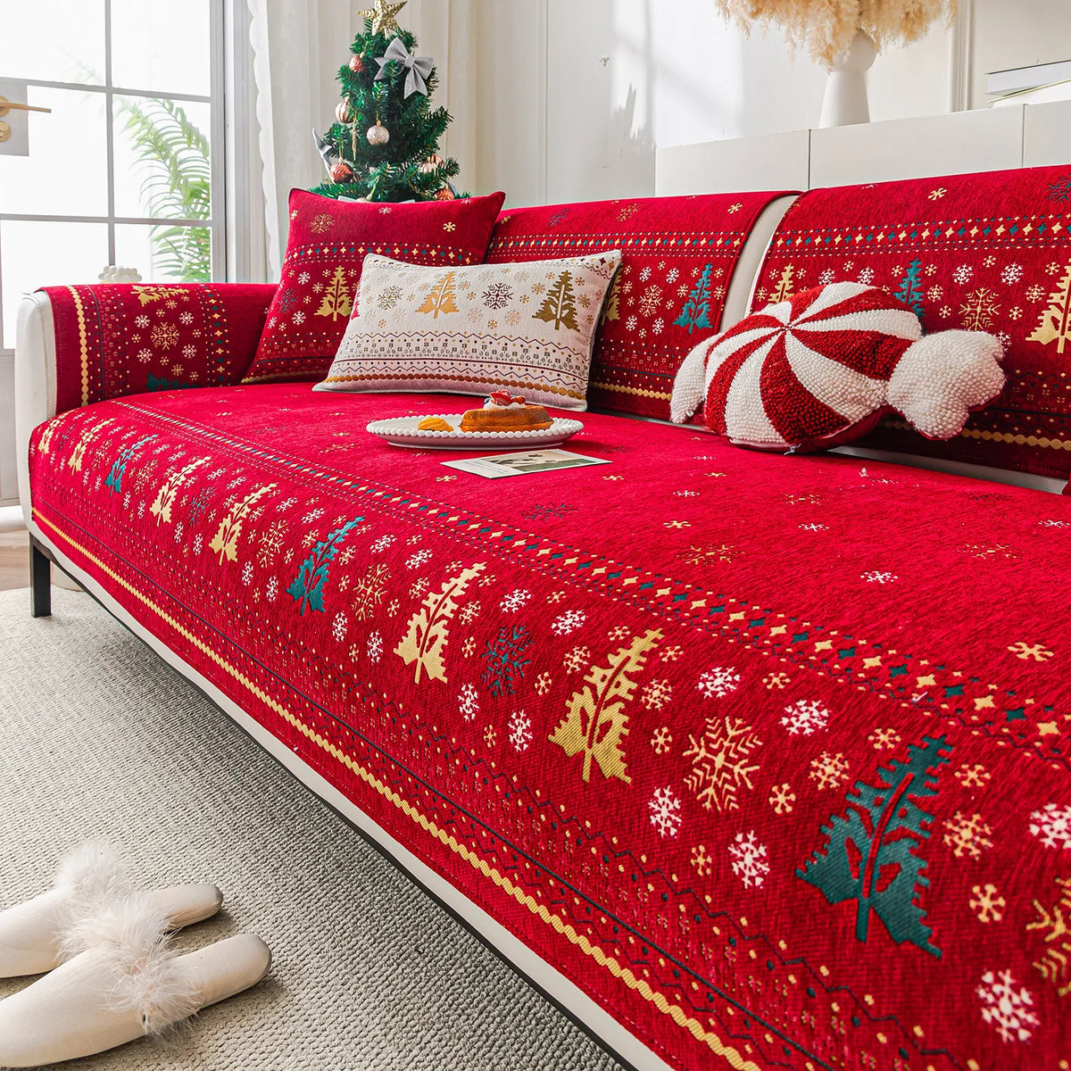A vibrant red Christmas tree patterned chenille sofa cover displayed on a bed with white and gold accents.