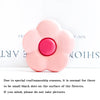 A pink flower-shaped foldable phone grip stand with small black dots on the surface.