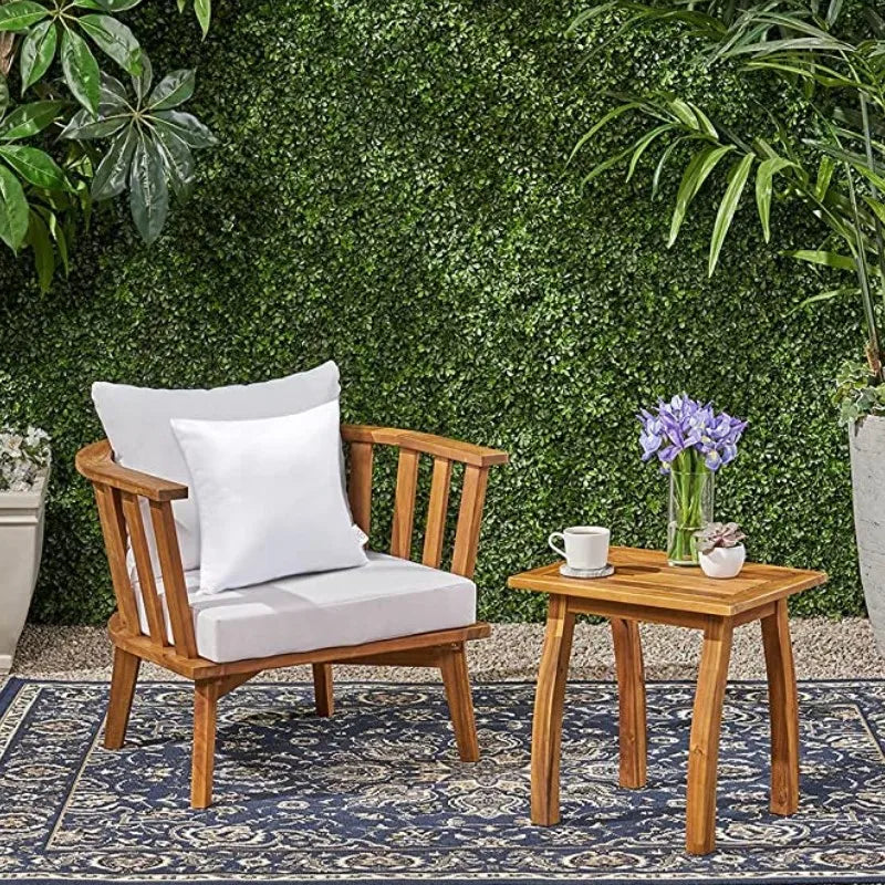 A wooden chair with a white cushion sits in front of a green moss wall and a small wooden table.