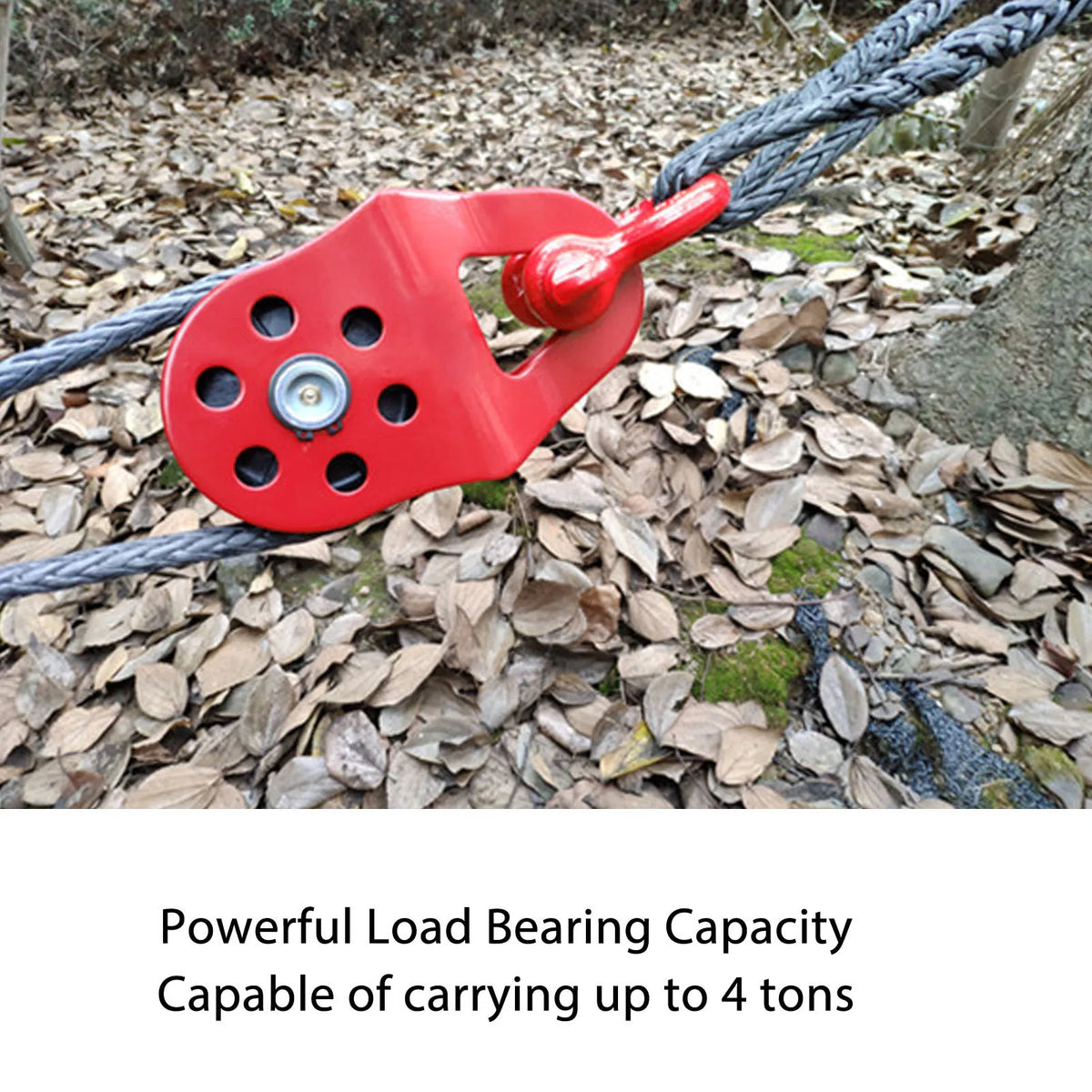 A red heavy duty snatch block is shown attached to a thick rope in an outdoor setting.