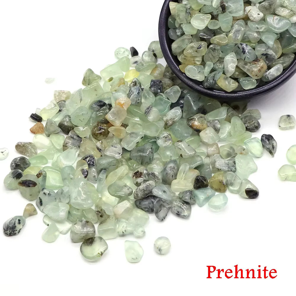 A pile of light green prehnite crystal chips and tumbled stones in a dark bowl.