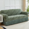 A teal jacquard sofa cover with a striped pattern and an elastic skirt displayed on a light rug.