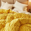 A bright yellow textured duvet cover and blanket with white pillows on a bed.