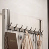 A silver over-the-door organizer rack with eight hooks mounted on a white wall panel.