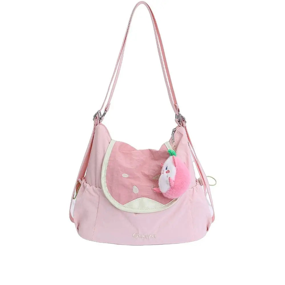 A pink nylon messenger bag with a light pink fabric pouch and a fluffy pink pom-pom charm.