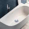 A white, oval bathtub features a circular silicone drain hair catcher installed on the side.
