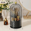 Organizador de vidrio negro para brochas de maquillaje con tapa dorada y patrón geométrico decorativo.