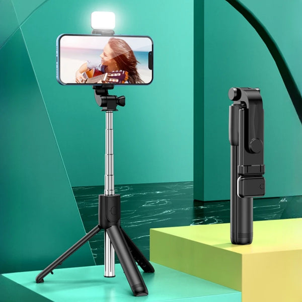 Schwarzes, ausziehbar-tragbares Stativ hält ein Smartphone zum Videoaufnehmen auf einer hellgrünen Fläche.