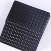A black playing card deck with a subtle geometric pattern and a matte finish.