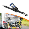 A black retractable ratchet tie-down strap with a blue handle is shown in context on a motorcycle.