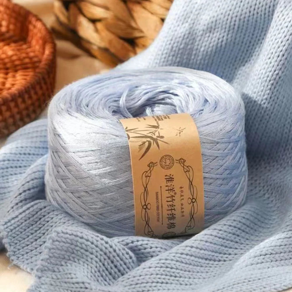 A ball of light blue pure cotton yarn for knitting and crochet resting on a blue knitted fabric.