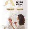 A woman is gently holding a baby while sitting on a bed, suggesting a peaceful and nurturing moment.