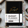 A5 budget planner with a black cover and white pages featuring stickers and planning layouts.