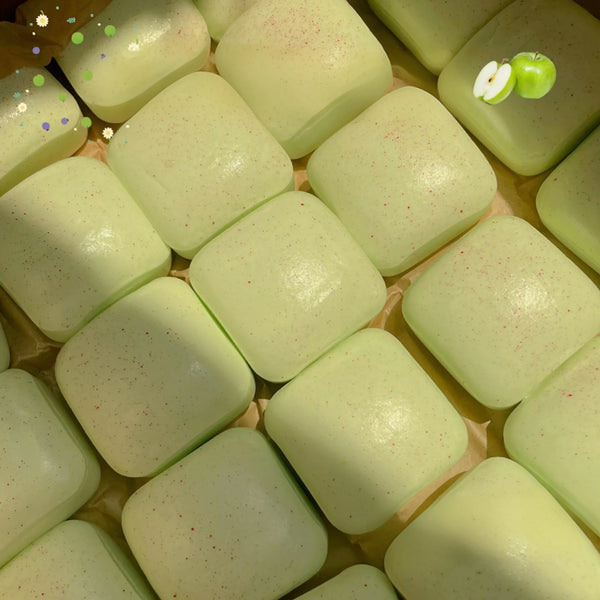 A close-up view of light green simulated square stress relief fidget toys arranged on a wooden surface.