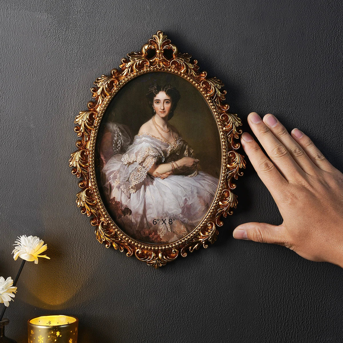 An ornate gold-framed portrait of a woman with white lace dress is displayed against a dark gray wall.