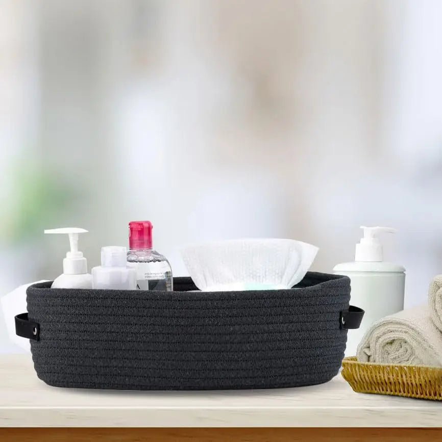 A dark gray woven cotton rope storage basket filled with various white and pink liquid and solid toiletries.