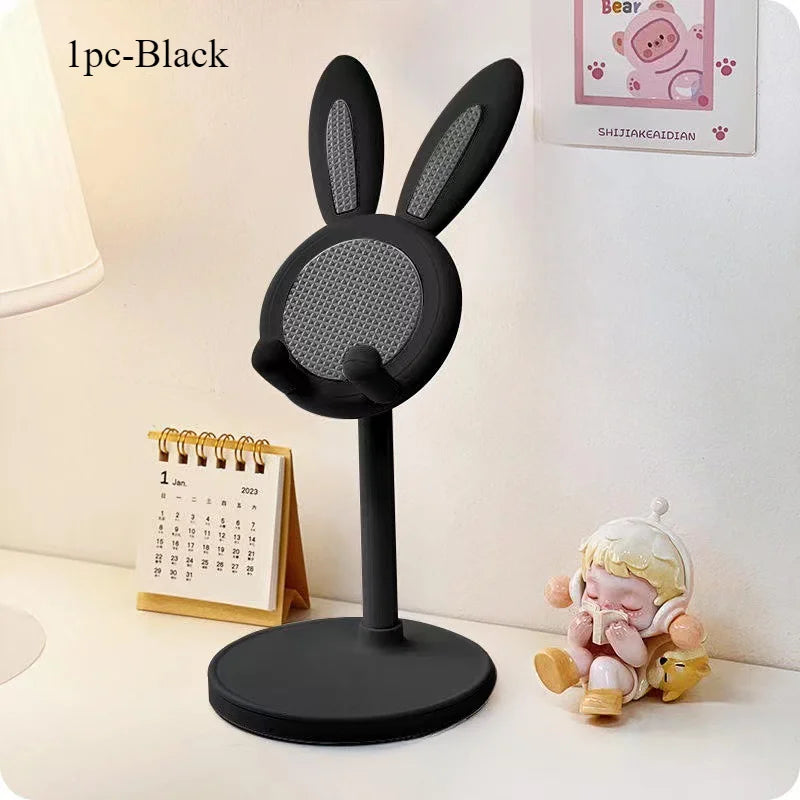 A black rabbit-shaped stand for a mobile phone or tablet, placed next to a calendar and a small plush toy.