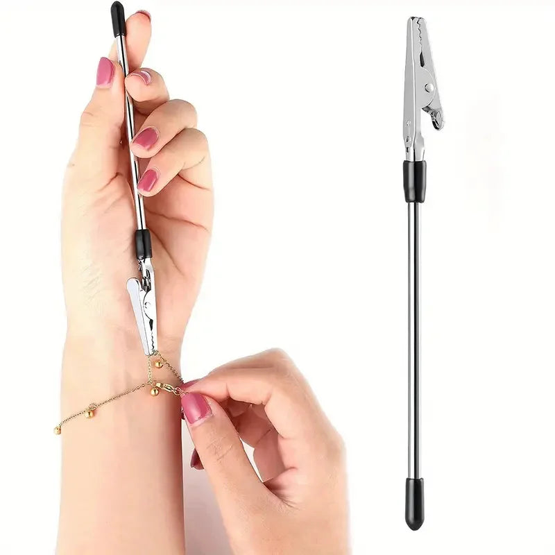 A hand holds a silver retractable bracelet fastening tool with a long metal rod and clamp.