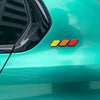 A close-up of a teal vehicle body featuring a horizontal tri-color emblem on the side panel.