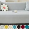 A light gray elegant jacquard sofa slipcover with decorative pillows and a floral accent.