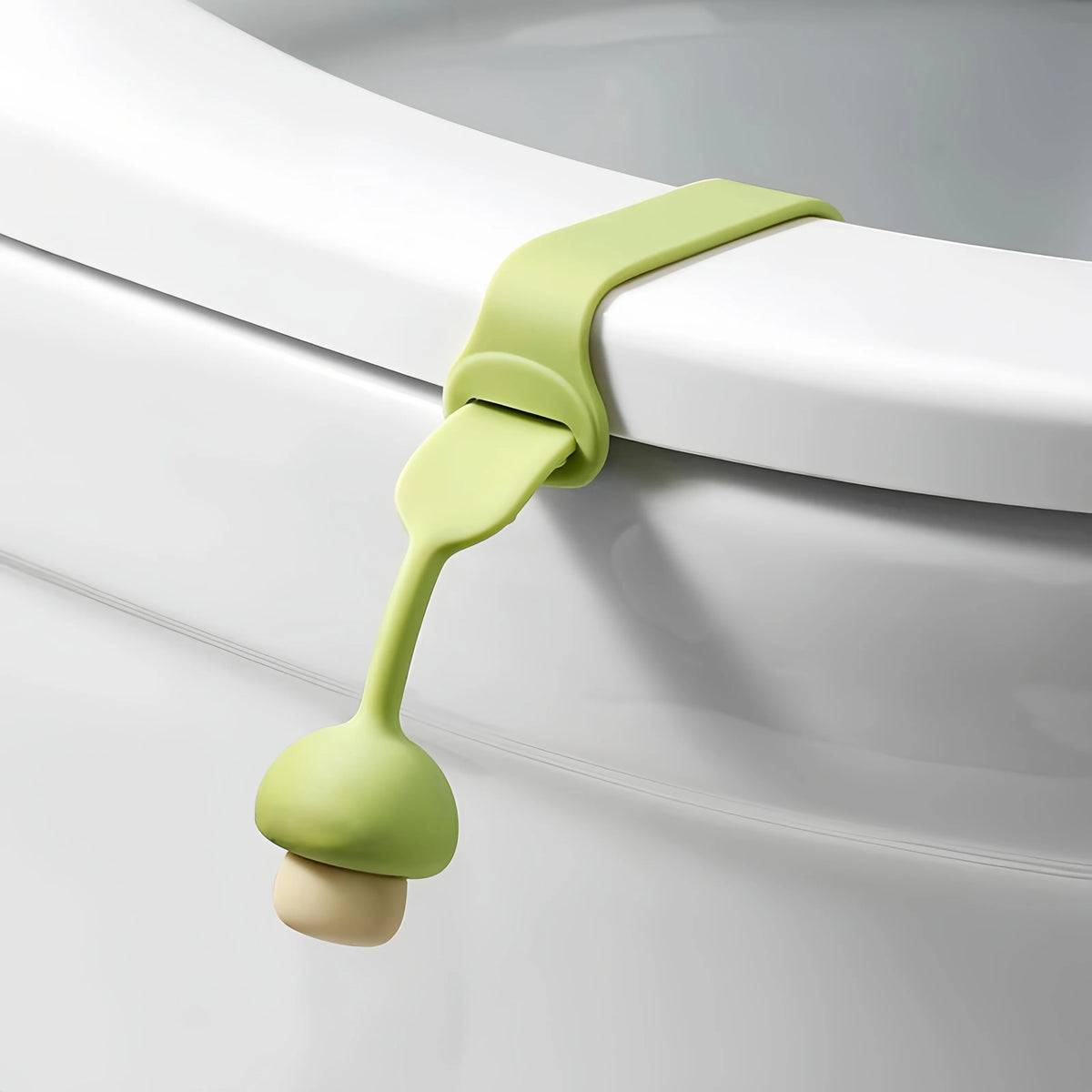 A silicone toilet seat lifter with a light green pull ring attached to a white porcelain fixture.
