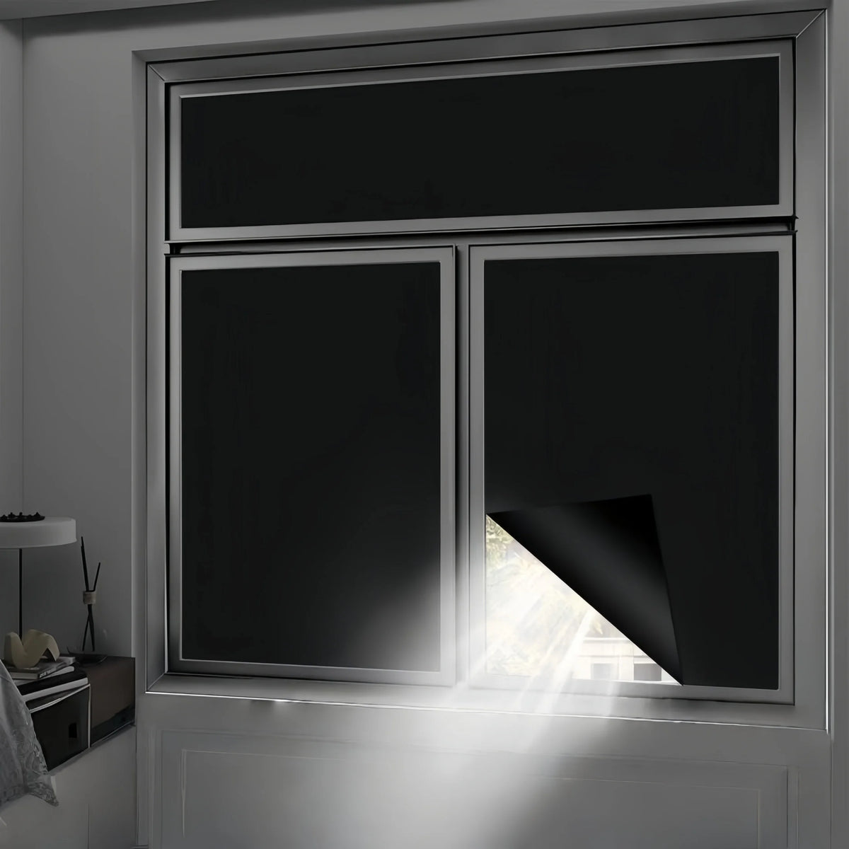A close-up view of a modern window with black privacy film installed, showing sunlight streaming through the glass.