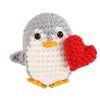 Handmade knitted penguin doll with a red heart attached