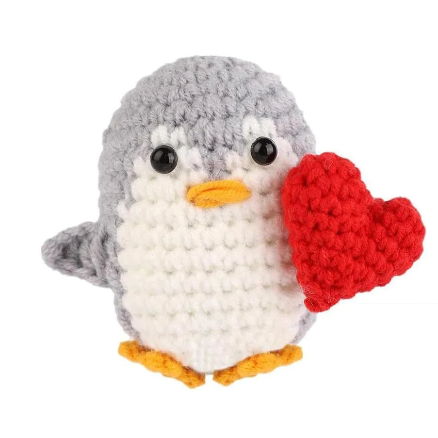 Handmade knitted penguin doll with a red heart attached