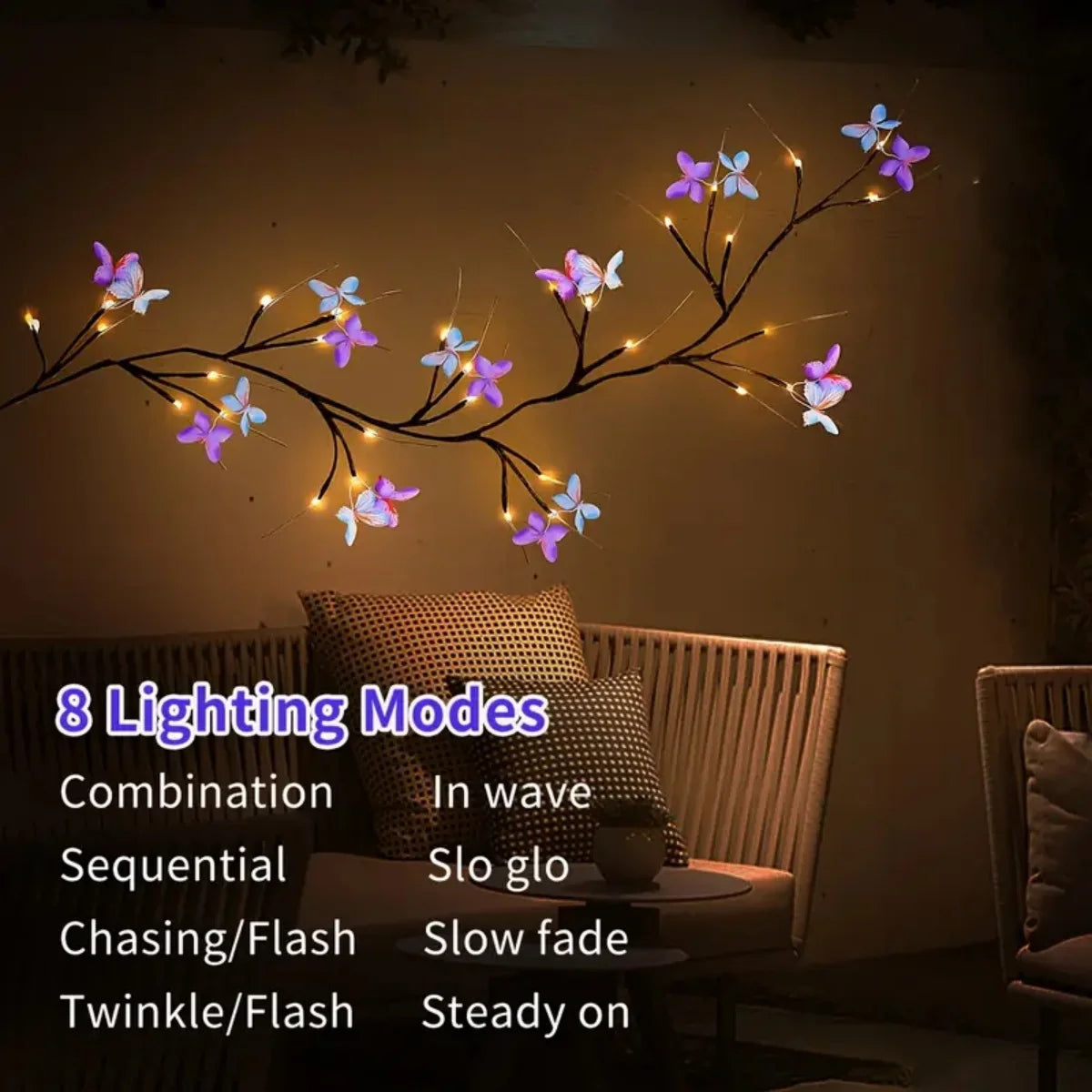 Une branche de vigne de saule avec des guirlandes lumineuses en papillons violets et bleus illuminant une pièce sombre.