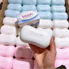 A hand holds white and pink stress relief squishy soap shaped fidget toys arranged in a box.