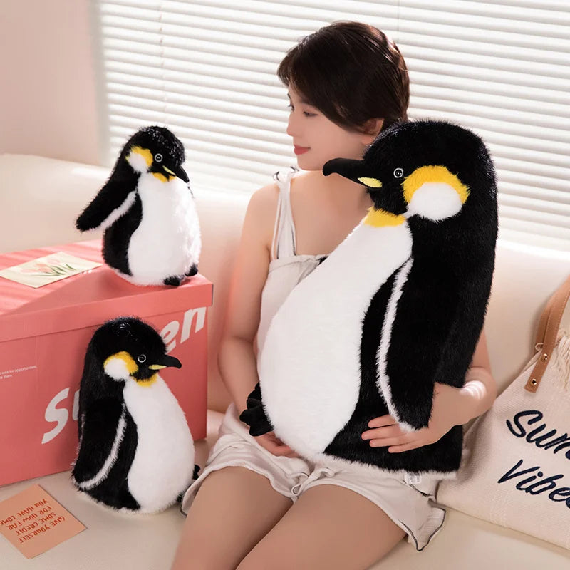 A woman is holding a black and white penguin plush toy in her arms, sitting on a light-colored sofa.
