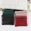 A set of five compact PU leather two-zip coin purses in various shades of green, black, pink, and red stacked on a light back