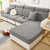 A gray stretch jacquard sofa cover with a leaf pattern displayed on a modern white sofa.