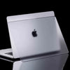 A silver laptop case for a MacBook is shown reflecting on a dark surface.