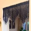 Black gothic lace curtain valance with silver fringe and tassels hanging over a window.