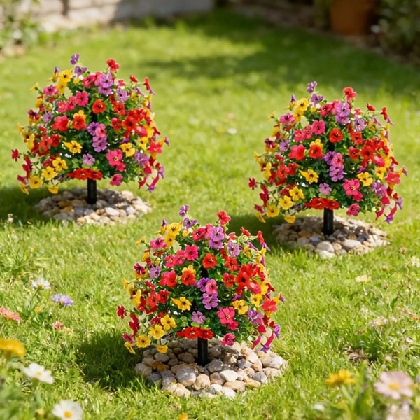 Three potted arrangements of colorful artificial garden flowers displayed in a grassy garden.