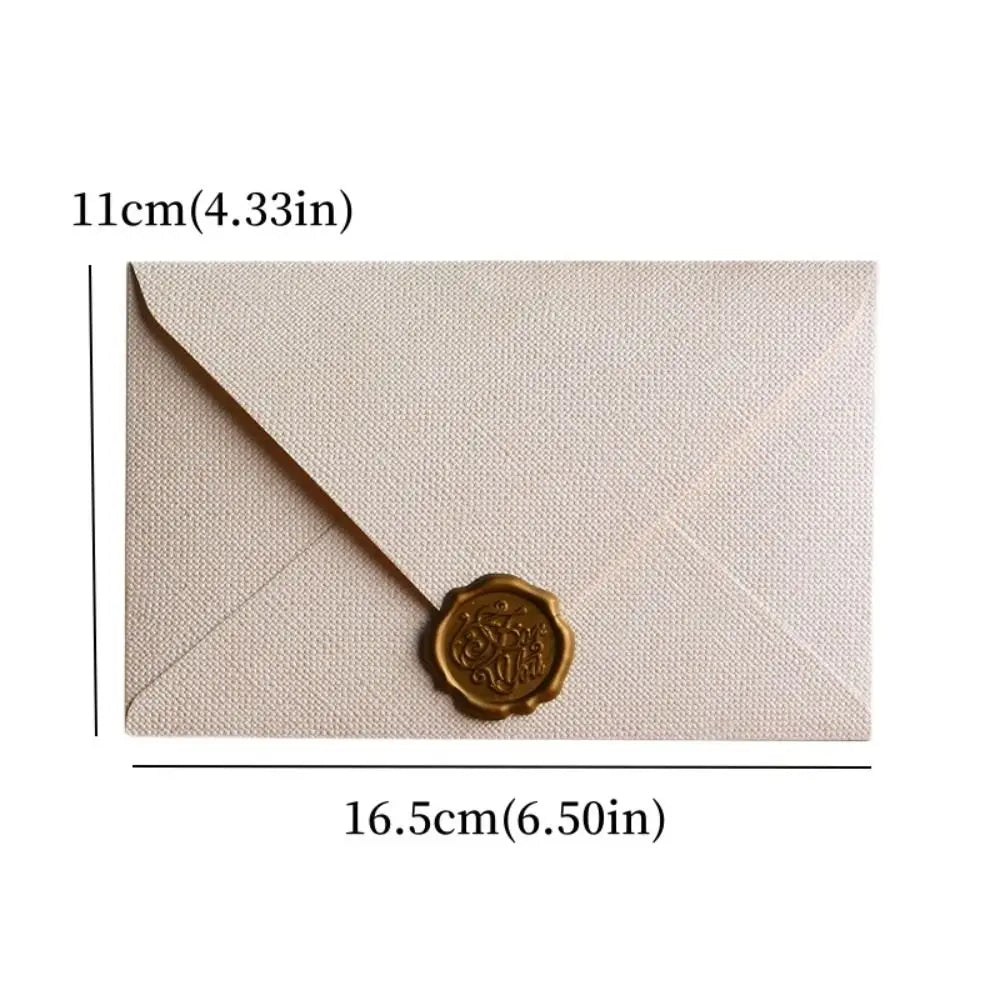 A pale beige linen texture envelope with a gold sealing wax sticker on the front.