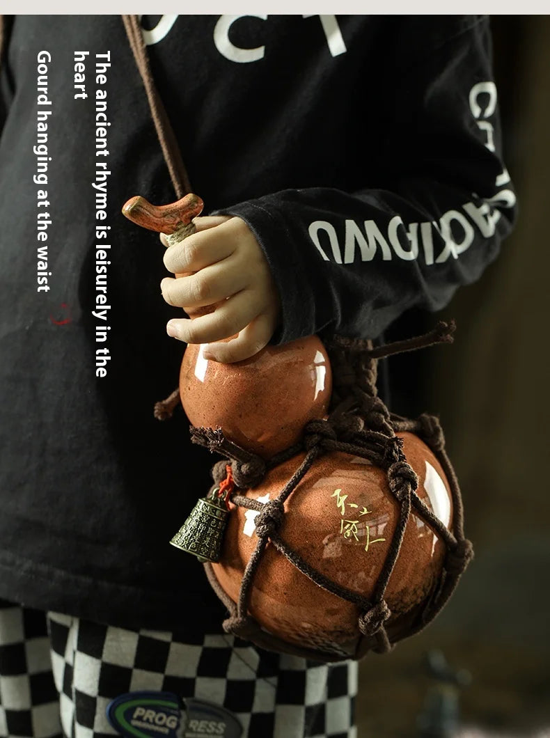 A person holds a handcrafted ceramic gourd wine set with a net bag against a dark background.