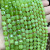 A hand holds a strand of light green natural stone square faceted beads for jewelry making.